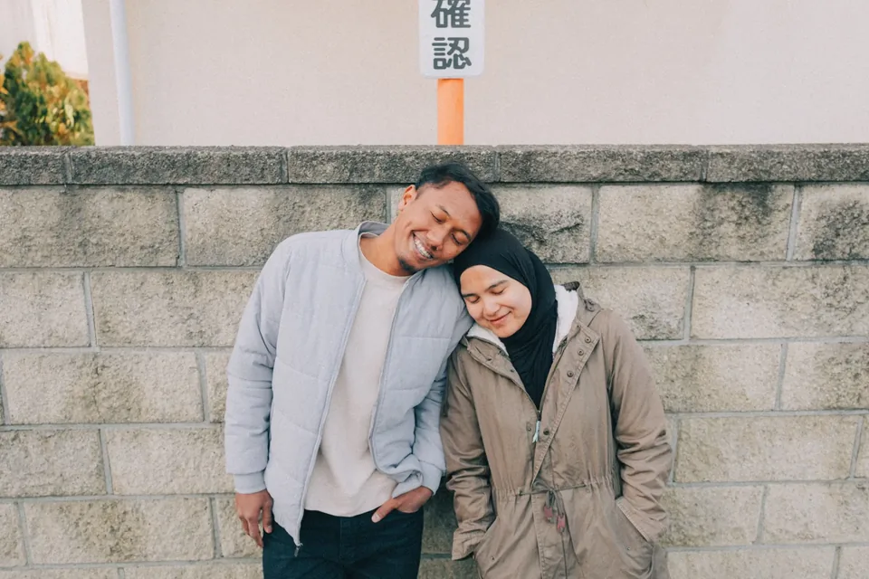 Couple resting together beside a stone wall