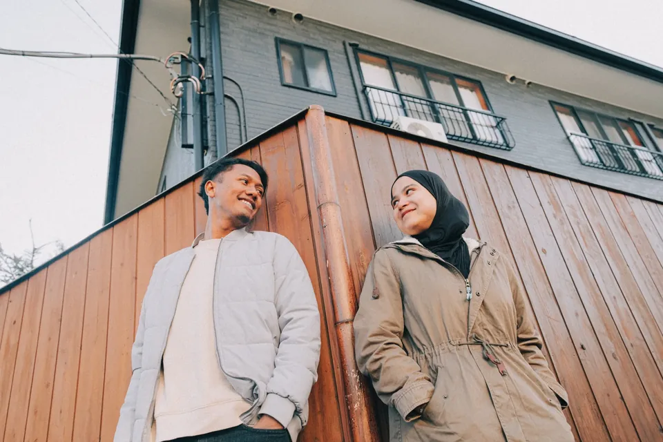 Couple sharing a smile beside a wooden wall